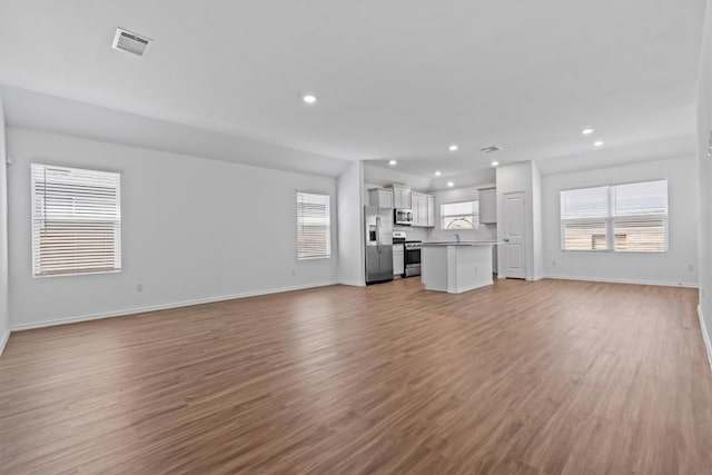 241 Madrid, Kyle, TX 78640 - unfurnished living room with recessed lighting, light wood-type flooring, and baseboards