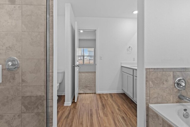 241 Madrid, Kyle, TX 78640 - full bathroom with vanity, a tile shower, a garden tub, and wood finished floors