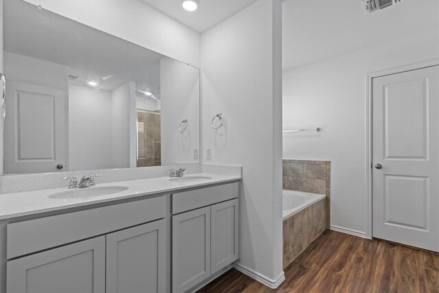 241 Madrid, Kyle, TX 78640 - full bathroom featuring wood finished floors, double vanity, a bath, and a tile shower