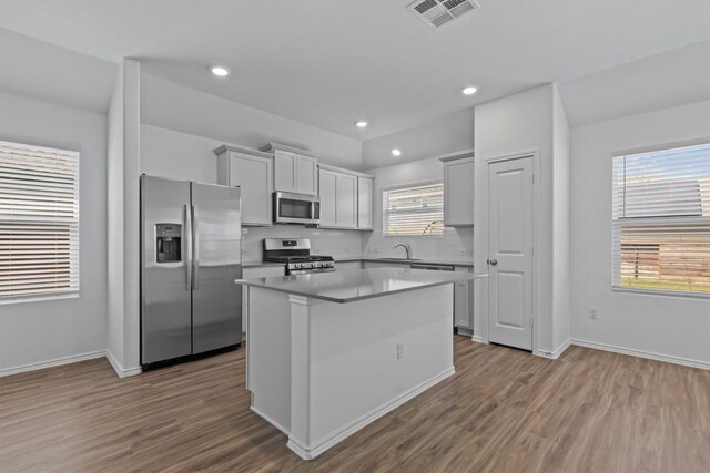 241 Madrid, Kyle, TX 78640 - kitchen featuring appliances with stainless steel finishes, a center island, a sink, dark wood-style flooring, and decorative backsplash