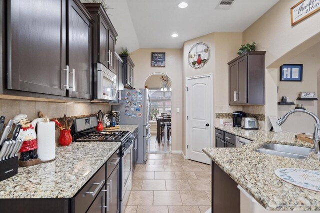 5627 Sabbia Dr, Round Rock, TX 78665 - kitchen with stainless steel appliances, recessed lighting, light stone countertops, dark brown cabinets, and light tile patterned flooring