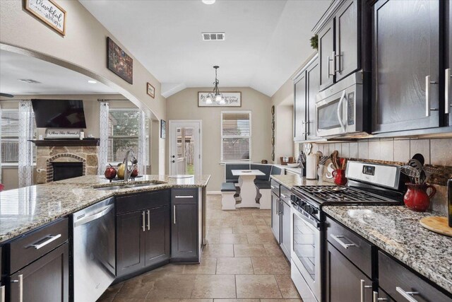 5627 Sabbia Dr, Round Rock, TX 78665 - kitchen with stainless steel appliances, decorative backsplash, open floor plan, light stone counters, and lofted ceiling