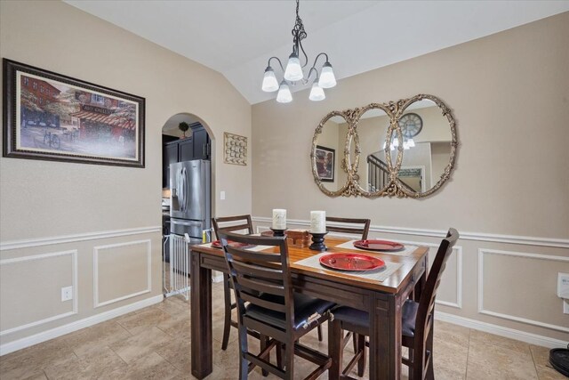 5627 Sabbia Dr, Round Rock, TX 78665 - dining space featuring a chandelier, a decorative wall, arched walkways, lofted ceiling, and wainscoting