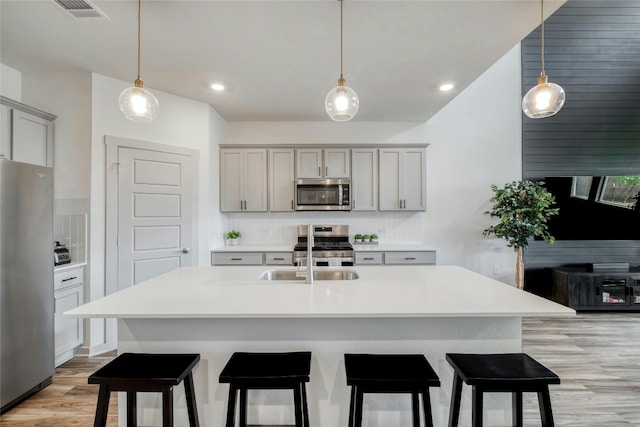 13901 Zuhause Dr, Pflugerville, TX 78660 - kitchen with stainless steel appliances, a sink, light wood-style floors, light countertops, and a kitchen bar