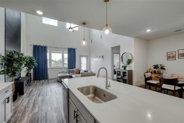 13901 Zuhause Dr, Pflugerville, TX 78660 - kitchen with a sink, stainless steel dishwasher, light countertops, hanging light fixtures, and light wood-type flooring