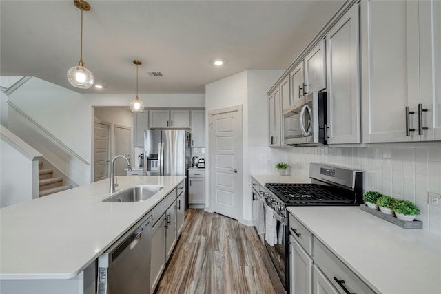 13901 Zuhause Dr, Pflugerville, TX 78660 - kitchen featuring stainless steel appliances, a sink, gray cabinetry, light countertops, and recessed lighting