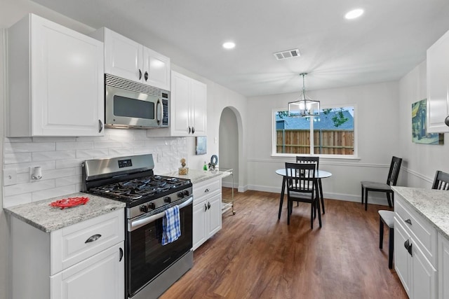 10802 Thicket Trl, Austin, TX 78750 - kitchen with stainless steel appliances, arched walkways, tasteful backsplash, dark wood finished floors, and white cabinetry
