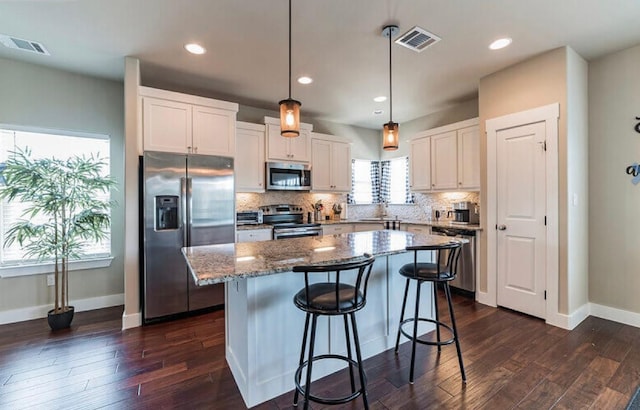 4301 Mansfield Dam Rd Unit 1102, Austin, TX 78734 - kitchen featuring appliances with stainless steel finishes, a sink, white cabinetry, a kitchen island, and tasteful backsplash