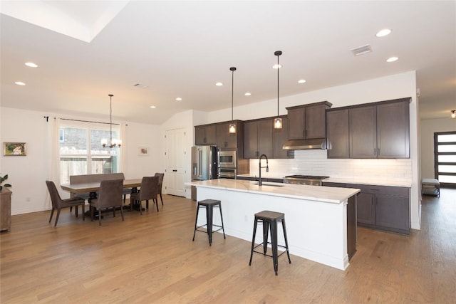 121 Split Oak Dr, Cedar Park, TX 78613 - kitchen with a sink, backsplash, a kitchen island with sink, light countertops, and dark brown cabinetry