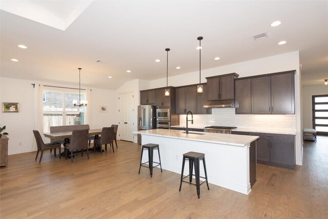 121 Split Oak Dr, Cedar Park, TX 78613 - kitchen featuring stainless steel appliances, a center island with sink, backsplash, light countertops, and dark brown cabinetry