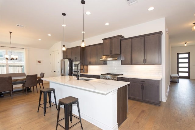 121 Split Oak Dr, Cedar Park, TX 78613 - kitchen featuring a sink, under cabinet range hood, stainless steel fridge with ice dispenser, tasteful backsplash, and dark brown cabinetry