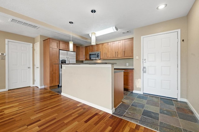 8888 Tallwood Dr Unit 1301, Austin, TX 78759 - kitchen featuring appliances with stainless steel finishes, baseboards, hanging light fixtures, brown cabinetry, and a kitchen island
