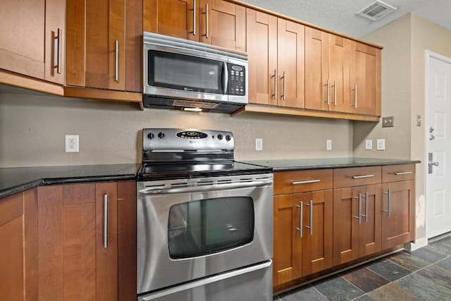 8888 Tallwood Dr Unit 1301, Austin, TX 78759 - kitchen featuring appliances with stainless steel finishes, dark countertops, and brown cabinetry