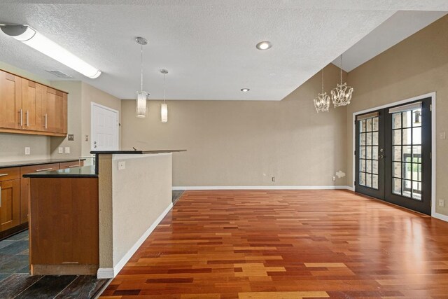 8888 Tallwood Dr Unit 1301, Austin, TX 78759 - kitchen with wood finished floors, baseboards, dark countertops, decorative light fixtures, and a chandelier