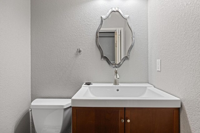 8888 Tallwood Dr Unit 1301, Austin, TX 78759 - half bathroom with vanity, toilet, and a textured wall