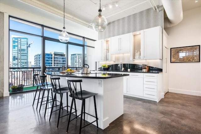 311 W 5th St W Unit 902, Austin, TX 78701 - kitchen with finished concrete flooring, dark countertops, a center island, a towering ceiling, and a breakfast bar