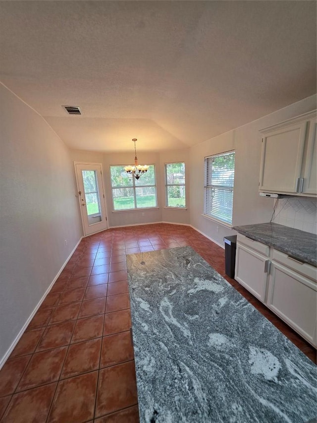 3401 Kissman Dr, Austin, TX 78728 - unfurnished dining area featuring a chandelier, healthy amount of natural light, dark tile patterned floors, and baseboards