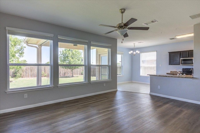 1519 Shenandoah Cv, Lockhart, TX 78644 - unfurnished living room featuring a chandelier, dark wood-style floors, ceiling fan, and baseboards