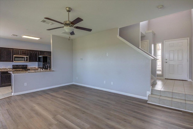 1519 Shenandoah Cv, Lockhart, TX 78644 - unfurnished living room with light wood finished floors, stairs, a ceiling fan, and baseboards