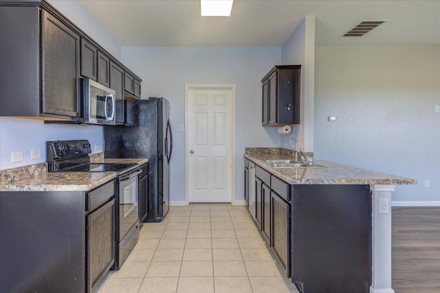 1519 Shenandoah Cv, Lockhart, TX 78644 - kitchen with black electric range oven, stainless steel microwave, a sink, a peninsula, and baseboards