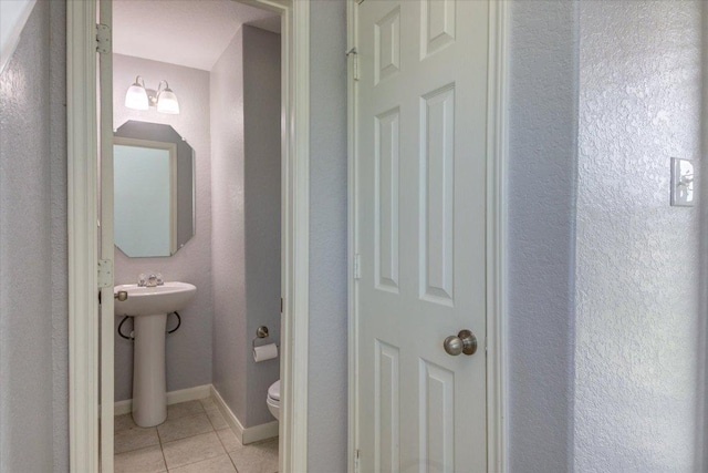 1519 Shenandoah Cv, Lockhart, TX 78644 - half bathroom featuring tile patterned flooring, toilet, baseboards, and a sink