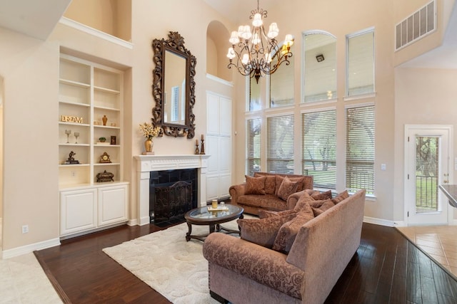 15 Sarazen Loop N, Georgetown, TX 78628 - living area with a high ceiling, healthy amount of natural light, a chandelier, a fireplace with flush hearth, and dark wood-style flooring