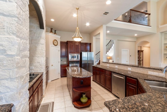 15 Sarazen Loop N, Georgetown, TX 78628 - kitchen with appliances with stainless steel finishes, open shelves, arched walkways, light tile patterned floors, and dark stone counters