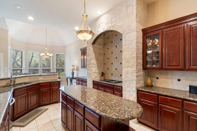 15 Sarazen Loop N, Georgetown, TX 78628 - kitchen featuring a chandelier, decorative light fixtures, backsplash, light tile patterned floors, and glass insert cabinets
