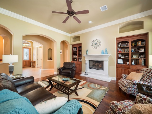 104 E Rustle Cv, Georgetown, TX 78628 - living area with built in features, arched walkways, wood finished floors, ceiling fan, and crown molding