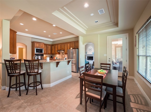 104 E Rustle Cv, Georgetown, TX 78628 - dining room featuring arched walkways, a tray ceiling, ornamental molding, recessed lighting, and baseboards