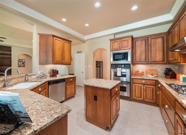 104 E Rustle Cv, Georgetown, TX 78628 - kitchen with stainless steel appliances, arched walkways, a sink, light stone counters, and brown cabinetry