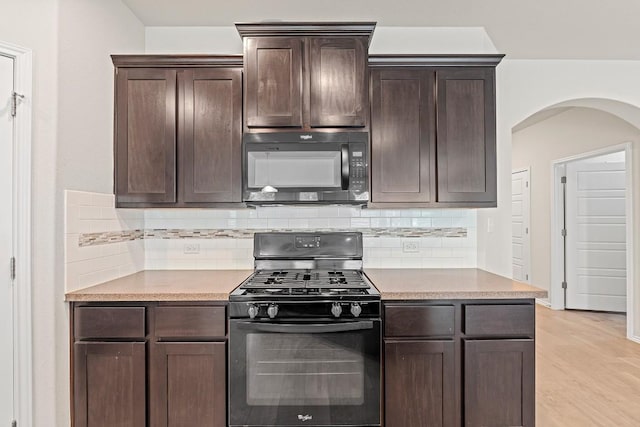 1012 Chad Loop, Round Rock, TX 78665 - kitchen with gas range, black microwave, arched walkways, dark brown cabinetry, and decorative backsplash