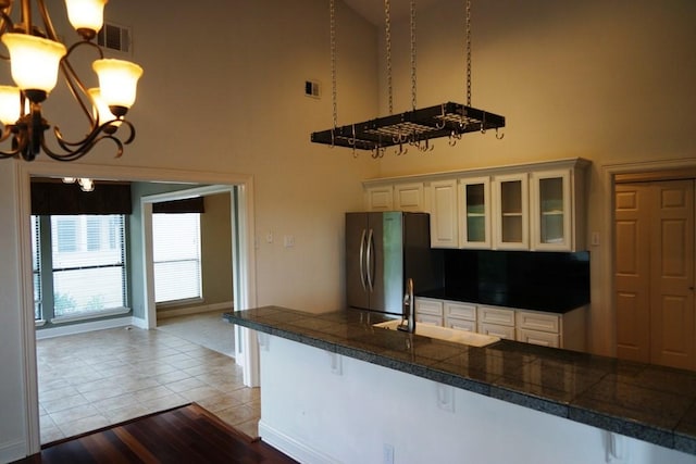 1520 Ben Crenshaw Way Unit 120, Austin, TX 78746 - kitchen with tile countertops, a high ceiling, freestanding refrigerator, a chandelier, and a sink