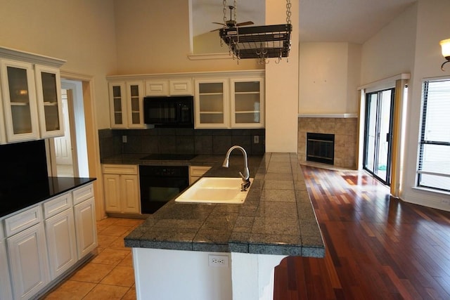1520 Ben Crenshaw Way Unit 120, Austin, TX 78746 - kitchen featuring black appliances, tile counters, a sink, ceiling fan, and a high ceiling
