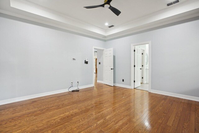 30418 La Quinta Dr, Georgetown, TX 78628 - empty room with wood finished floors, a raised ceiling, crown molding, a ceiling fan, and baseboards