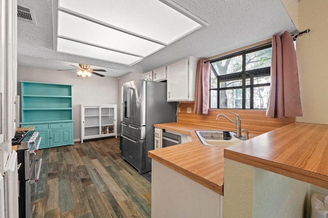 811 Timber Trl, Cedar Park, TX 78613 - kitchen featuring a sink, stainless steel appliances, a textured ceiling, dark wood finished floors, and a peninsula