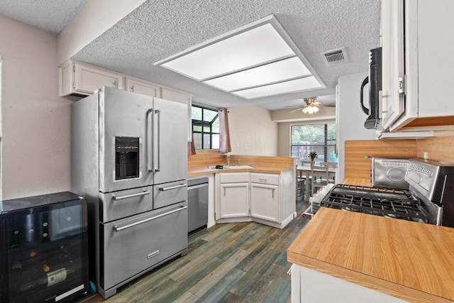 811 Timber Trl, Cedar Park, TX 78613 - kitchen with stainless steel appliances, wood counters, a textured ceiling, dark wood finished floors, and white cabinets