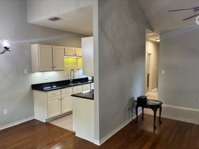 307 Quarry St, San Marcos, TX 78666 - kitchen with wood finished floors, dark countertops, white cabinetry, and lofted ceiling