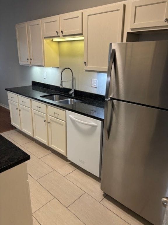 307 Quarry St, San Marcos, TX 78666 - kitchen with freestanding refrigerator, dishwasher, white cabinets, light tile patterned floors, and dark countertops