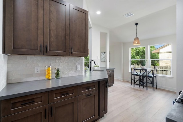 2012 Mimosa Trl, Round Rock, TX 78664 - kitchen with dark brown cabinets, backsplash, baseboards, decorative light fixtures, and light wood-style floors
