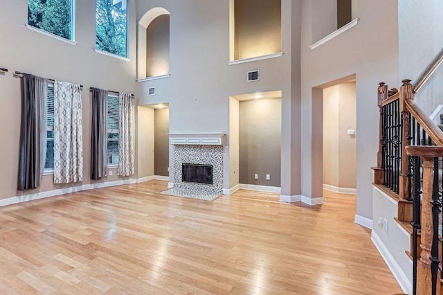 2607 Deep River Cir, Round Rock, TX 78665 - unfurnished living room featuring stairs, light wood finished floors, a high ceiling, a tiled fireplace, and arched walkways