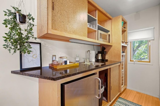 1406 Summit St, Austin, TX 78741 - kitchen with open shelves, wine cooler, a sink, light wood-style flooring, and dark stone countertops