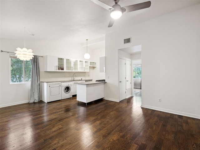 1503 W 9th St Unit 204, Austin, TX 78703 - kitchen with washer / dryer, vaulted ceiling, a sink, a peninsula, and glass insert cabinets