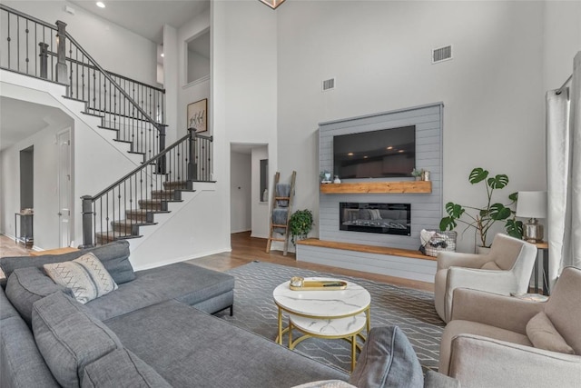 1626 Bearkat Canyon Dr, Dripping Springs, TX 78620 - living area featuring a high ceiling, wood finished floors, stairs, and a glass covered fireplace