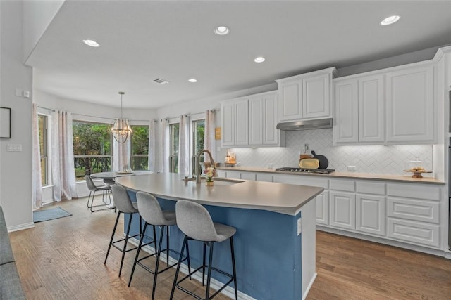 1626 Bearkat Canyon Dr, Dripping Springs, TX 78620 - kitchen with wood finished floors, white cabinets, stainless steel gas stovetop, and recessed lighting