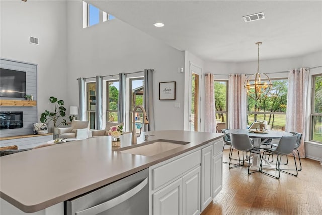 1626 Bearkat Canyon Dr, Dripping Springs, TX 78620 - kitchen with dishwasher, white cabinetry, a chandelier, light wood-style flooring, and hanging light fixtures