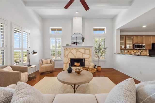 6201 River Place Blvd Unit 4, Austin, TX 78730 - living room featuring ceiling fan, plenty of natural light, dark wood-style flooring, a stone fireplace, and beam ceiling