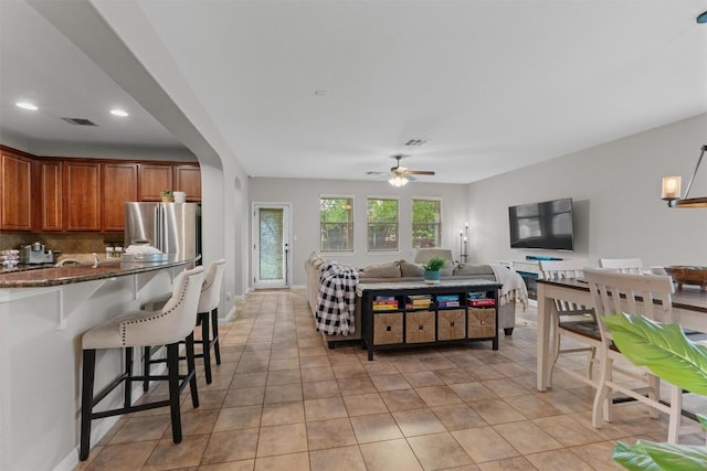 1017 Sussex Way, Round Rock, TX 78665 - kitchen featuring stainless steel refrigerator with ice dispenser, a kitchen breakfast bar, brown cabinets, ceiling fan, and decorative backsplash