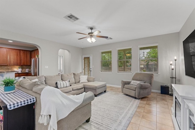 1017 Sussex Way, Round Rock, TX 78665 - living room with arched walkways, a ceiling fan, light tile patterned flooring, and baseboards
