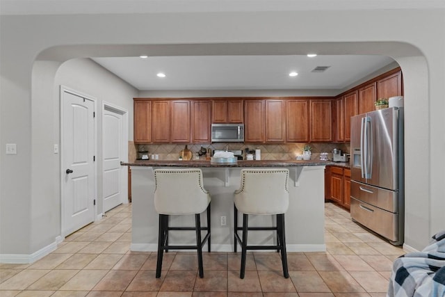 1017 Sussex Way, Round Rock, TX 78665 - kitchen with appliances with stainless steel finishes, arched walkways, backsplash, a breakfast bar, and light tile patterned flooring